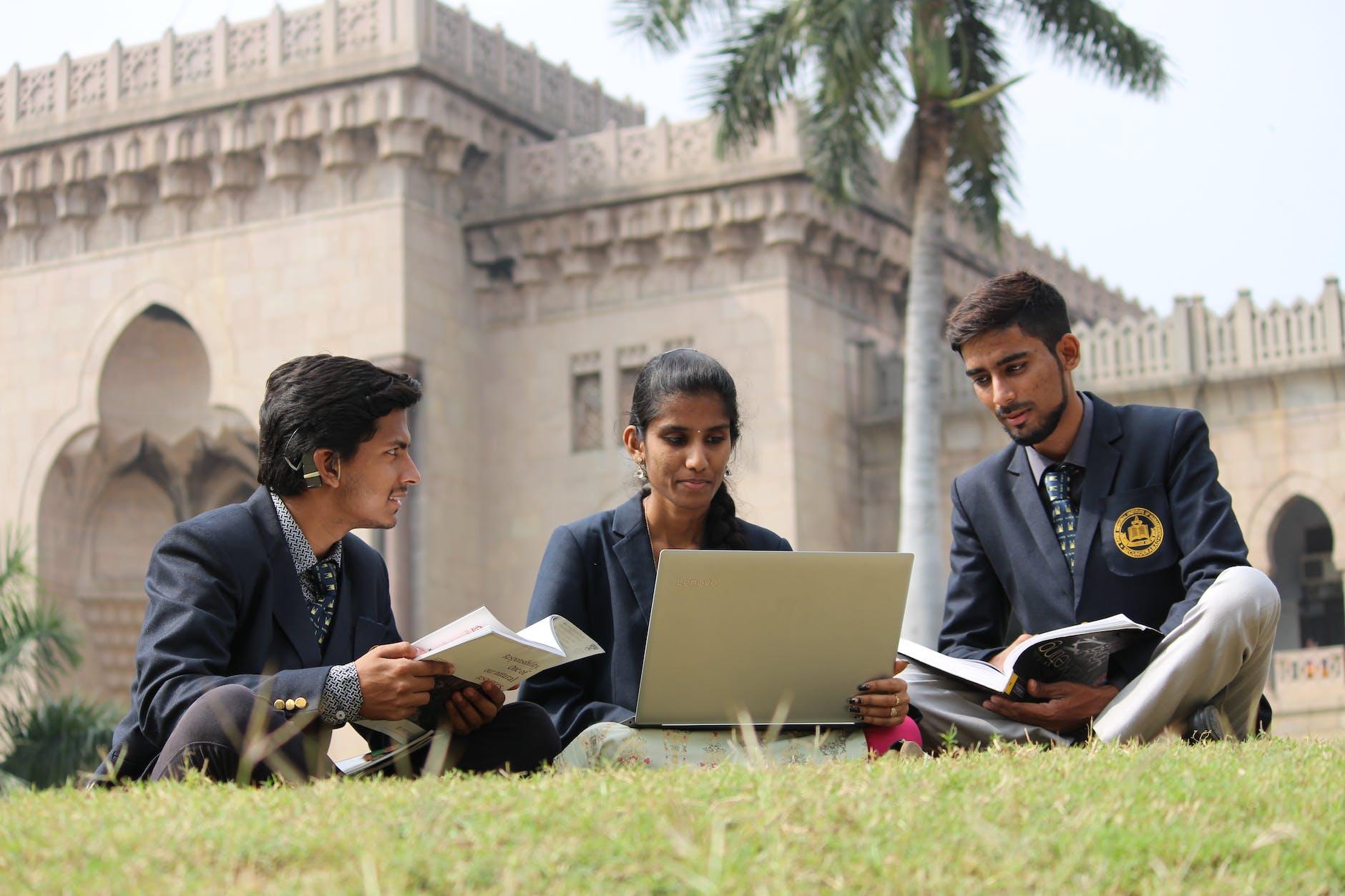 indian students doing homework in campus meadow